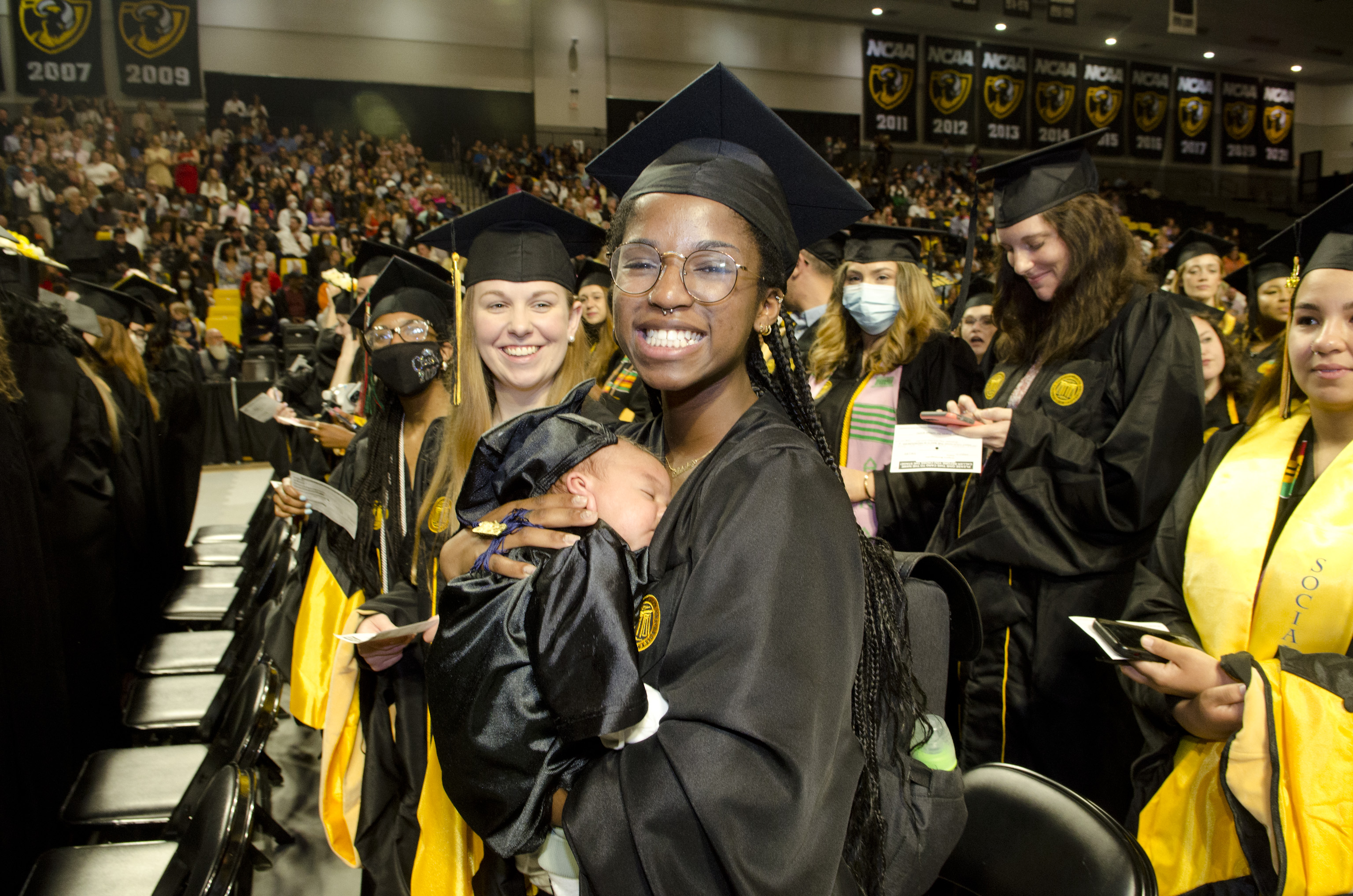 A graduate holds her baby during the May 2022 Commencement ceremony.