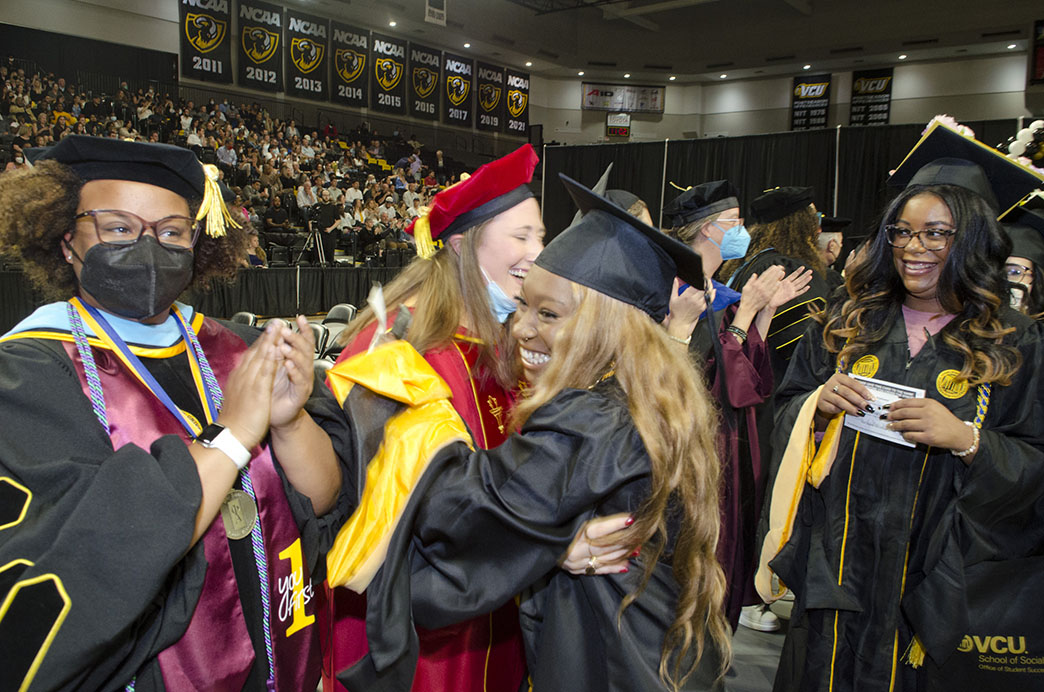 A graduate hugs assistant professor in teaching Cassie DeSena-Jacobs during the May 2022 Commencement ceremony.