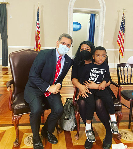 U.S. HHS Secretary Xavier Becerrra sits with alum Allison Gilbreath and her son, Perry, during a February 2022 visit to the White House