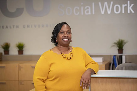 Shenita Williams rests her arm on a desk inside the VCU School of Social Work.