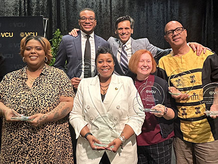 A group of six people stands holding awards.