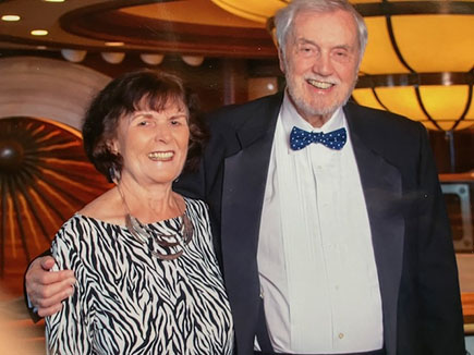 Rosemary Farmer wears a printed blouse and stands next to David Farmer, wearing a dark coat, white shirt and bowtie.