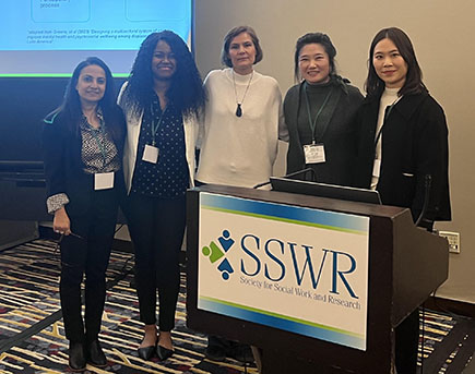 Five people stand in front of a podium with the sign: SSWR - Society for Social Work and Research