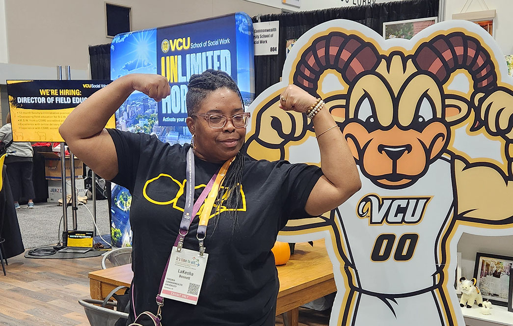 LaKesha Bennett flexes her muscles next to a life-sized cutout of mascot Rodney the Ram.